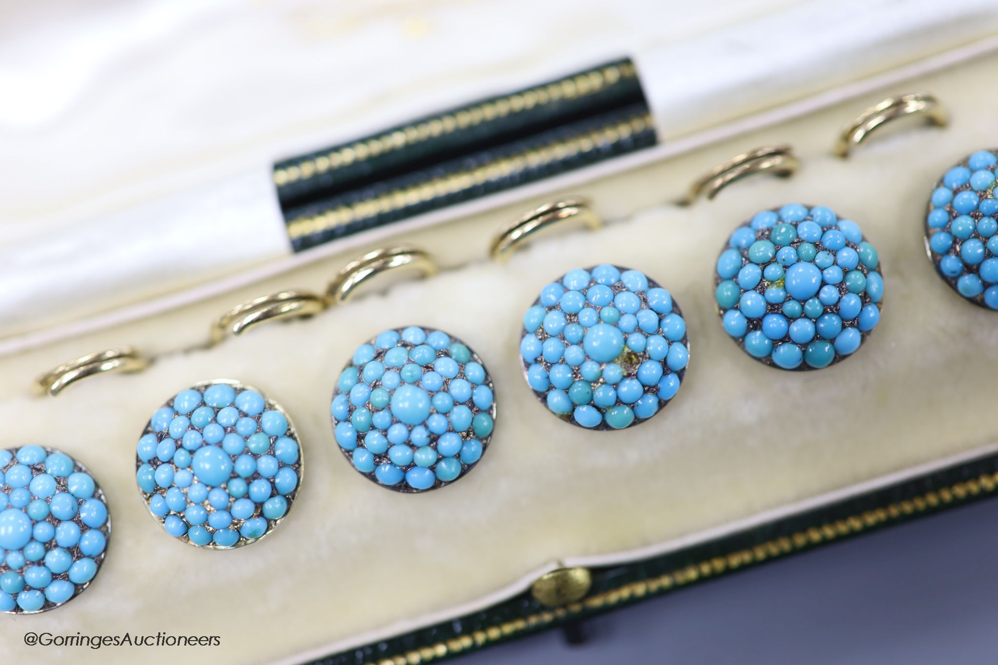 An early 20th century cased set of six yellow metal and turquoise set dress studs (stone missing)